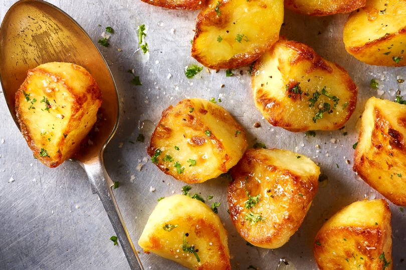 Roast potatoes served on a baking tray with herbs